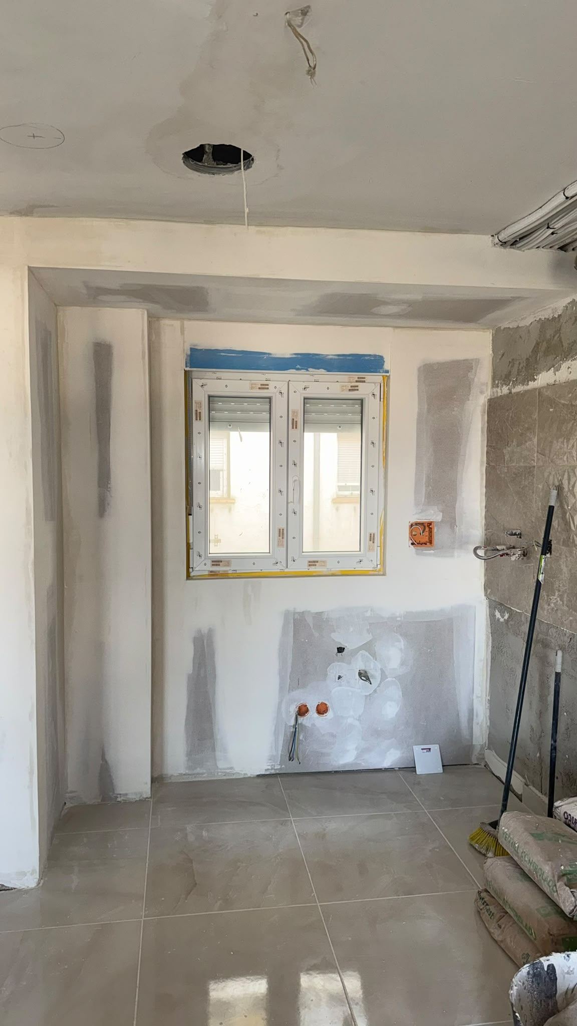 Baño en obra con las paredes trasdosadas en pladur y el hueco de la ventana emboquillado
