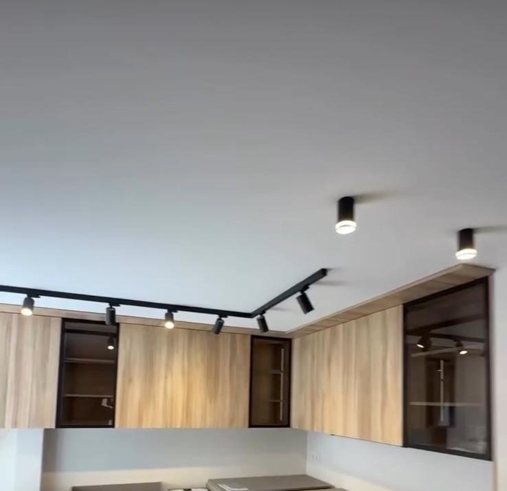 Cocina con muebles de madera y techo liso con carril negro de focos orientables