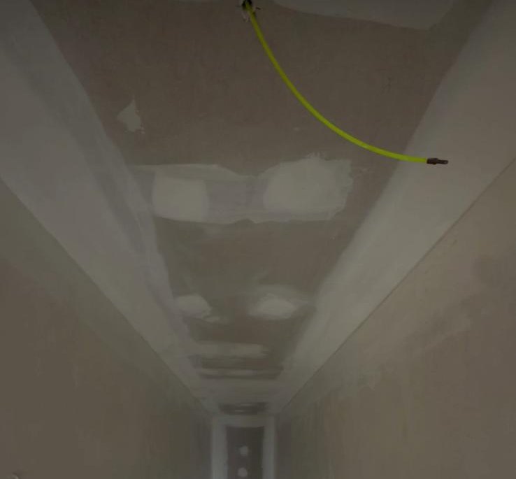 Falso techo de pladur que sigue la pendiente del hueco de una escalera, con las juntas emplastecidas