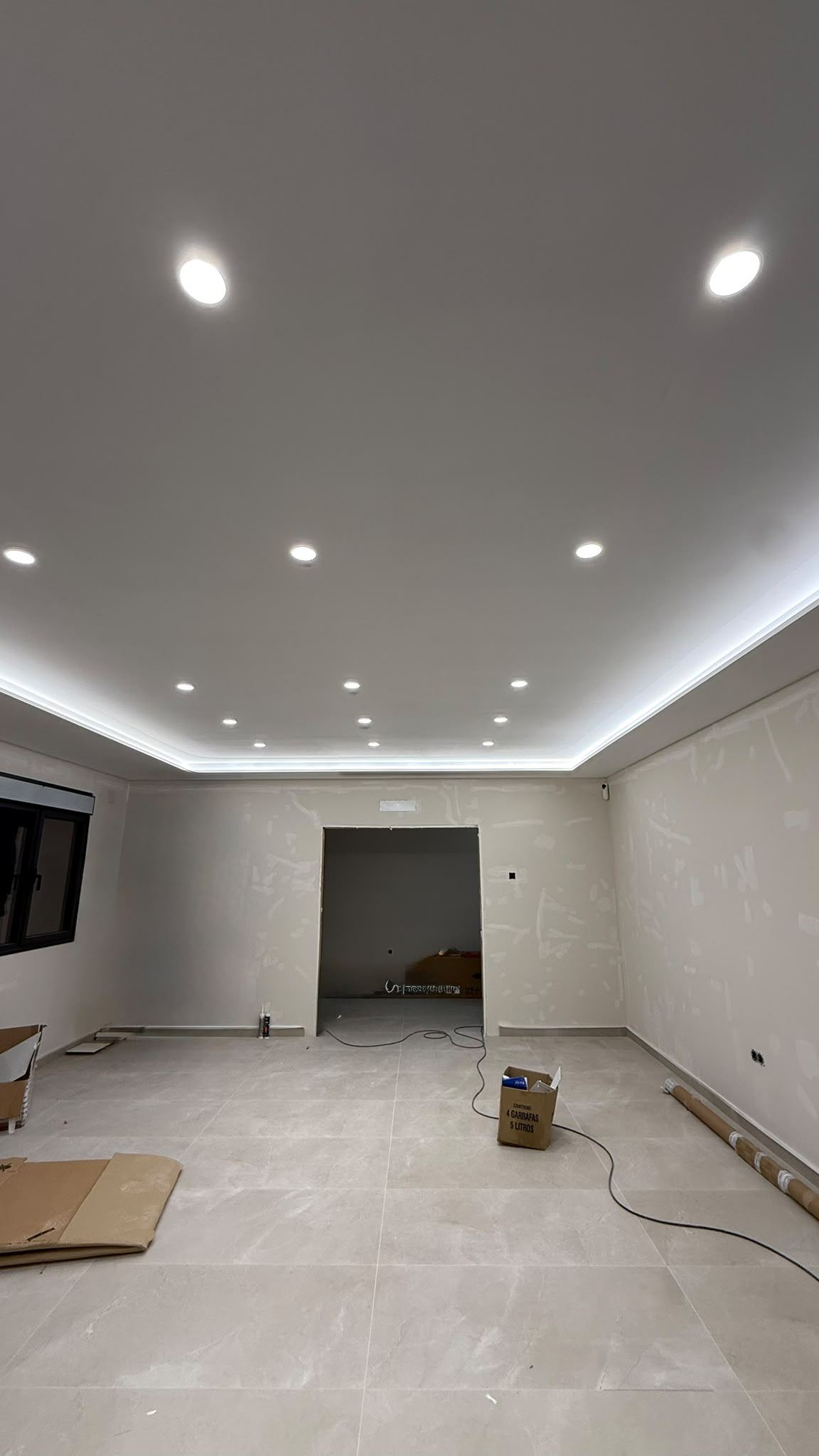 Salón amplio con falso techo de pladur, foseado perimetral con tira LED encendida y focos empotrados