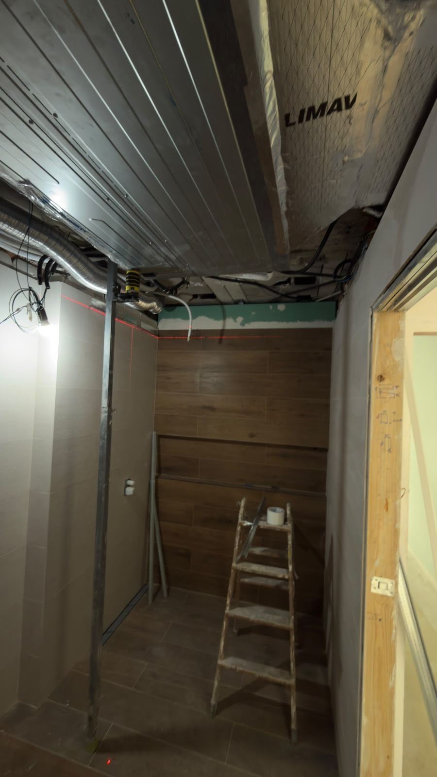Estancia con el techo abierto: chapa, conductos y cables a la vista y la perfilería de pared ya colocada
