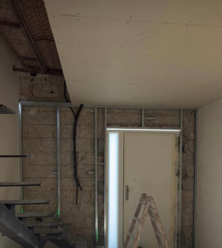 Estructura de perfiles metálicos para cerrar con pladur el hueco junto a una escalera y una puerta de entrada