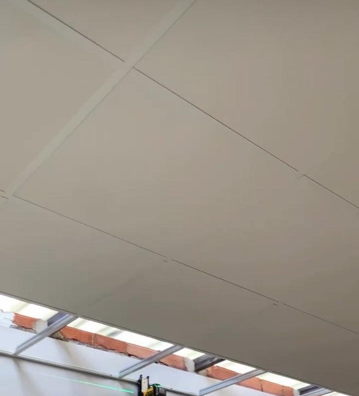 Techo registrable de placas sobre perfilería vista en una oficina, con el nivel láser montado